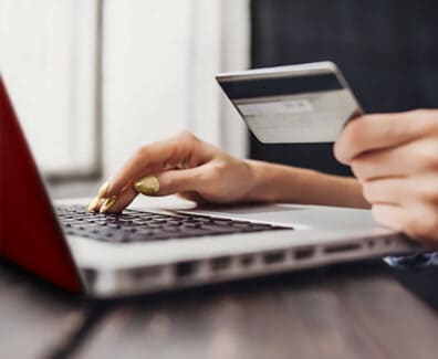 Mujer escribiendo en la computadora portátil y con tarjeta de crédito