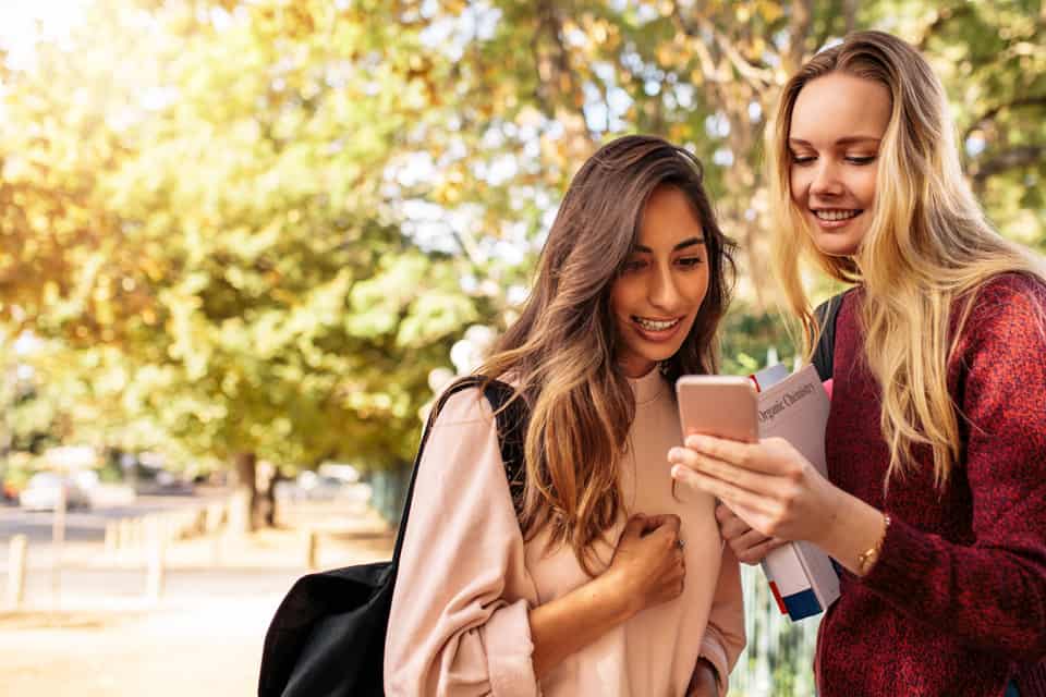 Two female students look at something on a mobile phone