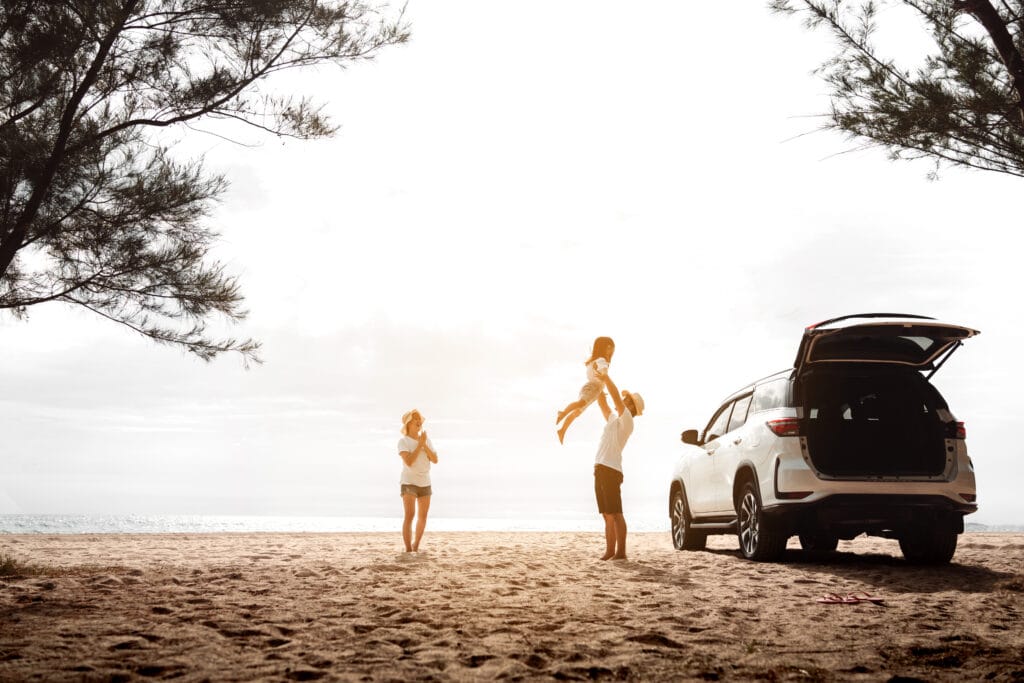 woman, man and toddler standing next to a truck with the trunk open