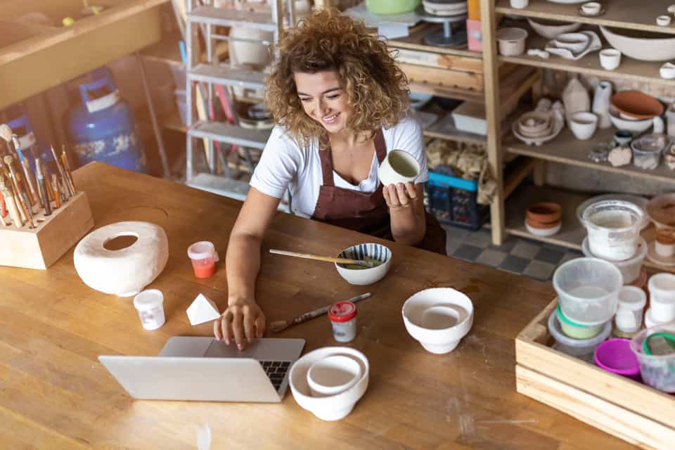 Woman paints pottery in a studio